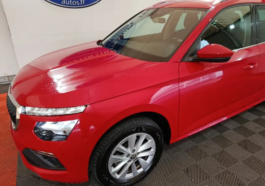Vue 3/4 avant droit d'un Skoda Kamiq rouge 2024 avec phares LED et jantes alliage argentées.