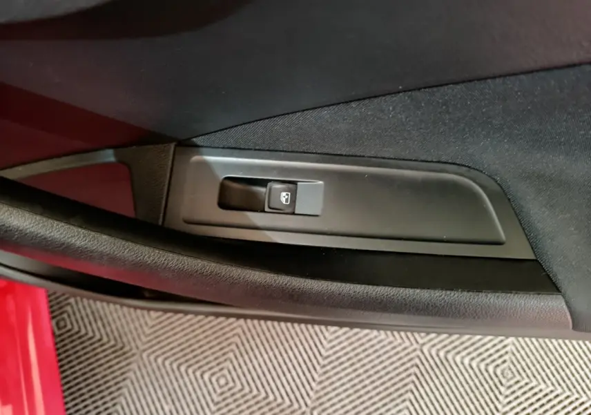 Détail de la commande de lève-vitre côté conducteur sur porte intérieure d’un Skoda Kamiq rouge.