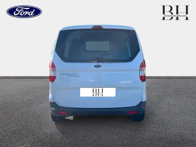 Vue arrière du Ford Transit Courier Fourgon blanc Glacier avec hayon arrière vitré et bouclier noir.
