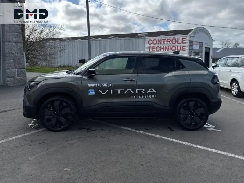 Vue de profil côté gauche du Suzuki Vitara électrique 2026 en vert Land Breeze avec toit noir et lettrage distinctif sur la porte.