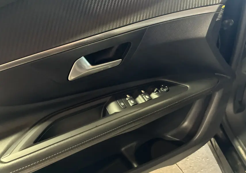 Vue intérieure côté gauche de la porte avant noire du Peugeot 3008 2020, avec commandes électriques des vitres et poignée argentée.