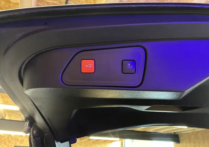 Boutons de commande du hayon électrique et du verrouillage des sièges arrière, vus sous le coffre du Peugeot 3008 noir 2020.