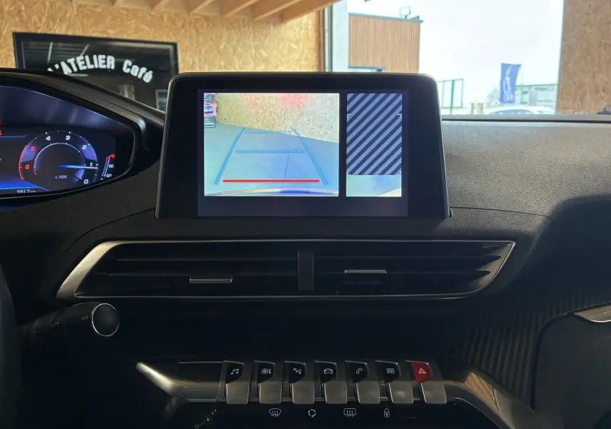Vue intérieure du tableau de bord du Peugeot 3008 noir, écran central affichant la caméra de recul avec lignes de guidage.
