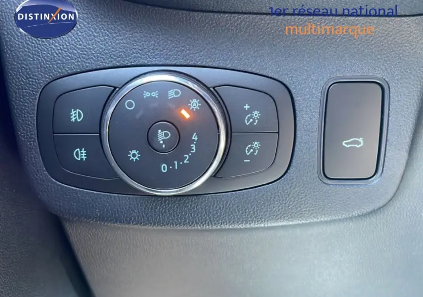 Gros plan sur les commandes d’éclairage et ouverture du coffre dans l’habitacle noir d’une Ford Puma 2023 gris Solar Metal.