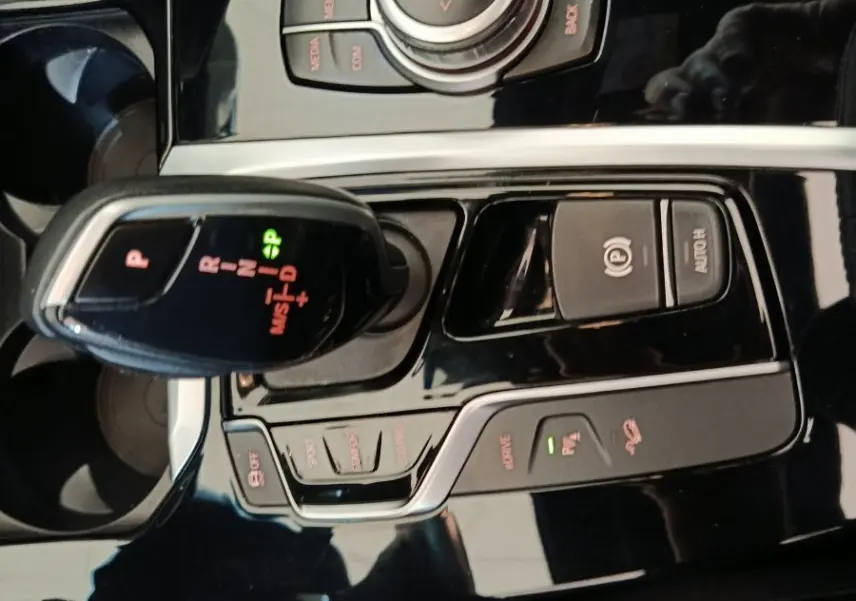 Vue rapprochée de la console centrale noire brillante du BMW X3 xDrive30e avec levier de vitesses et molette de contrôle.