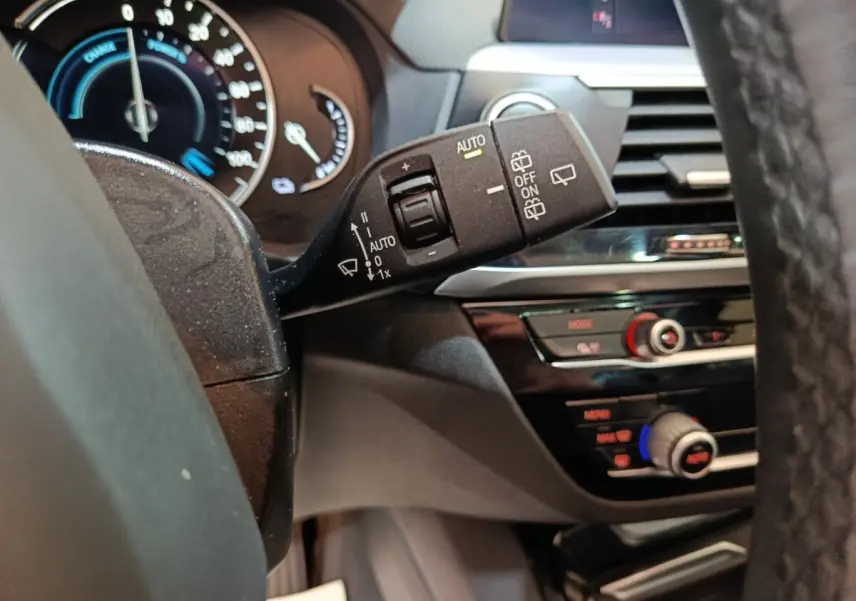 Gros plan sur la commande d’essuie-glace côté gauche du tableau de bord d’une BMW X3 gris foncé, intérieur moderne.