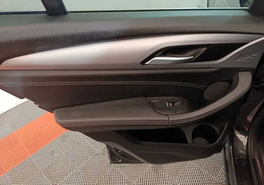 Vue intérieure côté gauche de la porte BMW X3 xDrive30e 2020, garniture noire avec insert argenté et surpiqûres blanches.