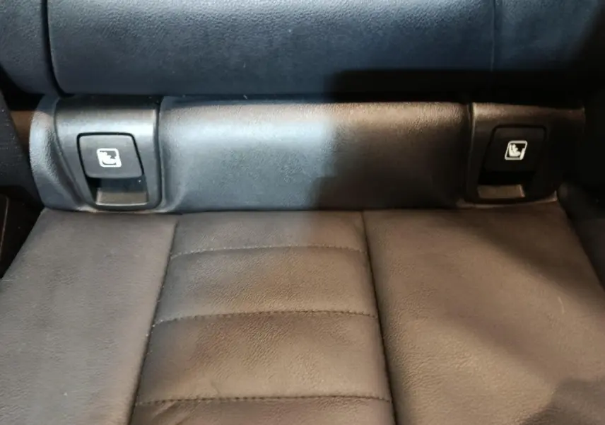 Gros plan sur les commandes de rabattement des sièges arrière en cuir noir du BMW X3 xDrive30e gris foncé.