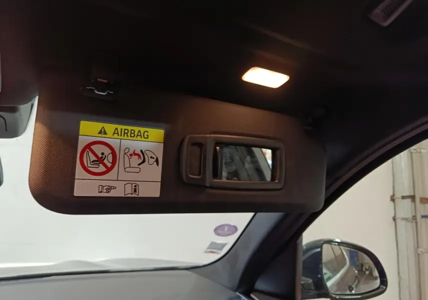 Détail du pare-soleil côté conducteur avec miroir intégré et avertissement airbag, intérieur noir du BMW X3 gris foncé.