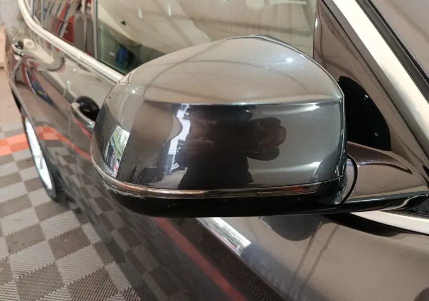 Gros plan sur le rétroviseur côté gauche gris foncé du BMW X3 xDrive30e 2020 avec carrosserie brillante et jante visible.