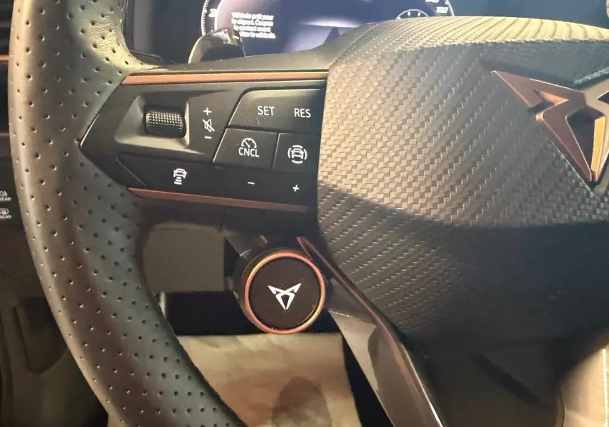 Gros plan sur le volant cuir perforé noir du CUPRA Formentor 2.0 TDI 150 DSG avec commandes intégrées et logo central.