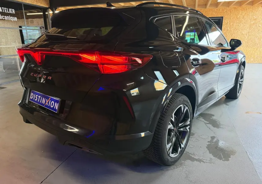 Vue 3/4 arrière droite d'un CUPRA Formentor noir avec jantes alliage 18'' TEMPEST et feux arrière LED allumés.