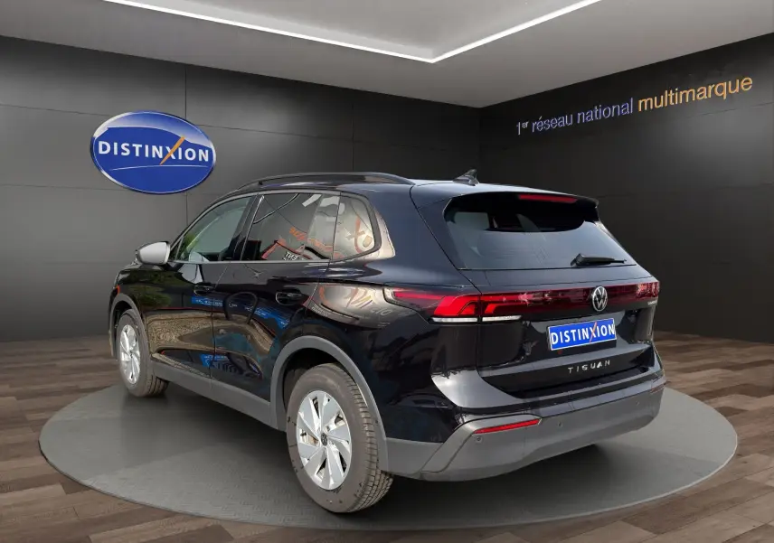 Vue 3/4 arrière droite d'un Volkswagen Tiguan noir 2024 avec feux arrière LED et vitres surteintées.