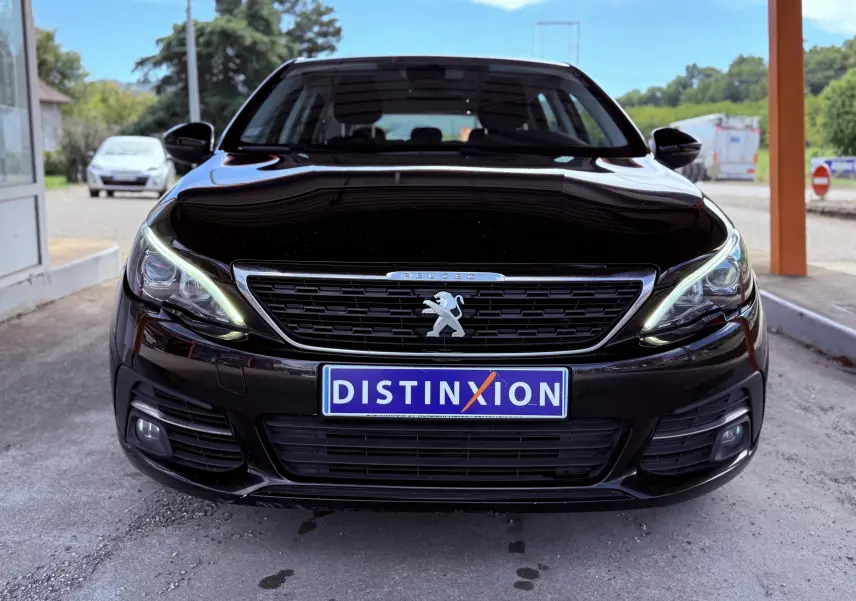 Vue frontale d'une Peugeot 308 SW noire métal avec feux LED allumés et plaque Distinxion visible.