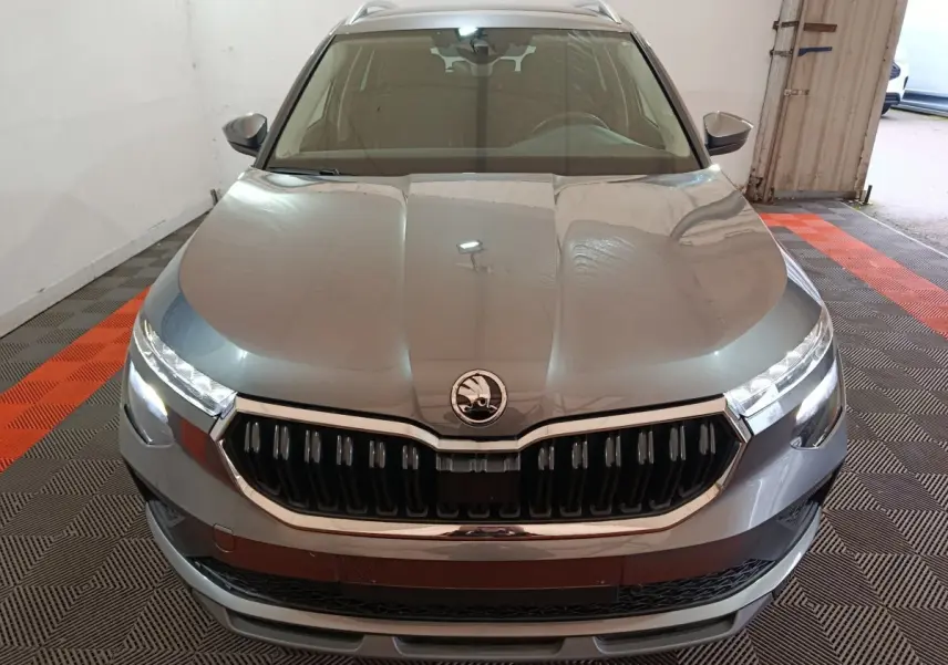 Vue frontale d'un Skoda Kamiq gris clair avec calandre chromée et phares LED allumés dans un garage.
