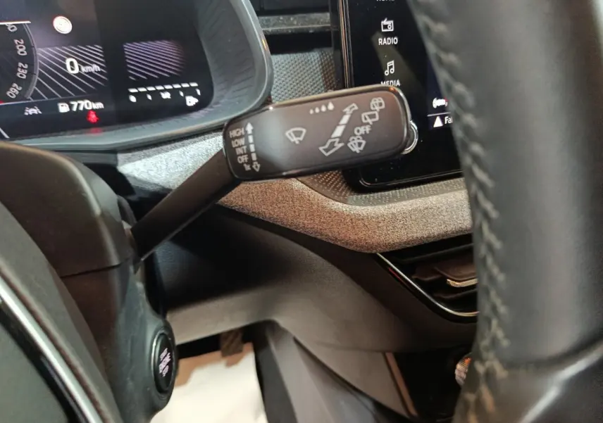 Gros plan sur la manette d'essuie-glace à gauche du volant cuir dans l'habitacle du Skoda Kamiq gris clair 2024.