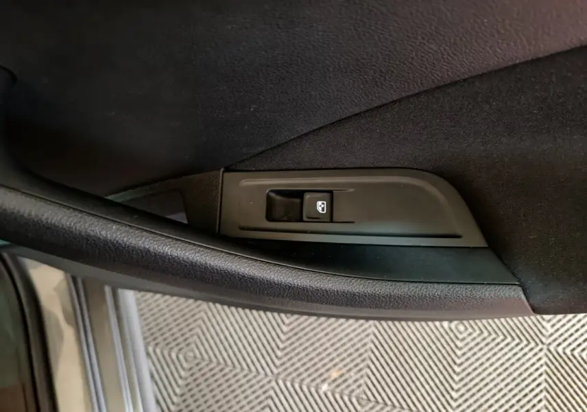 Gros plan sur le bouton de lève-vitre électrique côté gauche dans l’habitacle noir du Skoda Kamiq gris clair 2024.