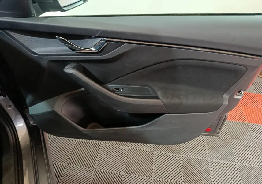 Vue côté gauche de la porte avant gris clair d’un Skoda Kamiq 2024 avec poignée chromée et rangement intégré.