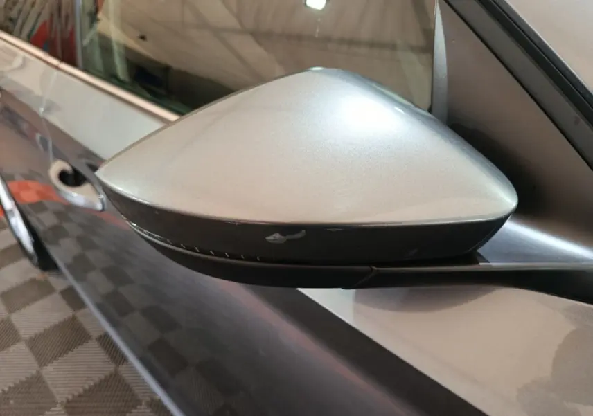 Gros plan sur le rétroviseur droit gris clair d'une Skoda Kamiq 2024, avec carrosserie assortie visible en arrière-plan.