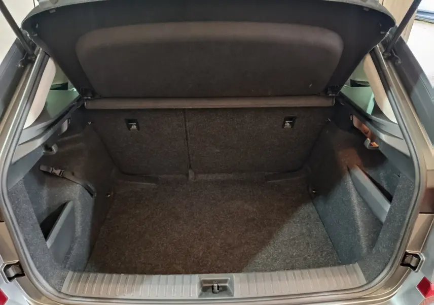 Coffre ouvert vu de l'arrière du Skoda Kamiq gris clair 2024, espace de chargement vide et tapis gris.