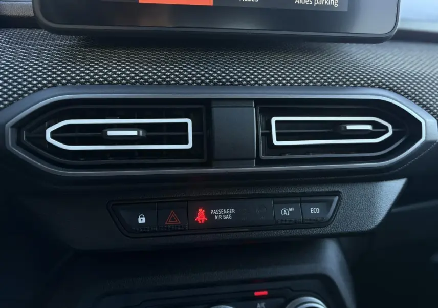 Vue rapprochée des aérateurs centraux et des boutons de contrôle du tableau de bord du Dacia Jogger gris Schiste 2025.