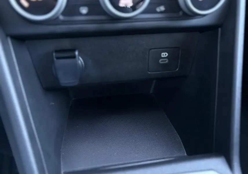 Gros plan sur la console centrale noire du Dacia Jogger 2025 avec prise USB-C et port 12V visible.