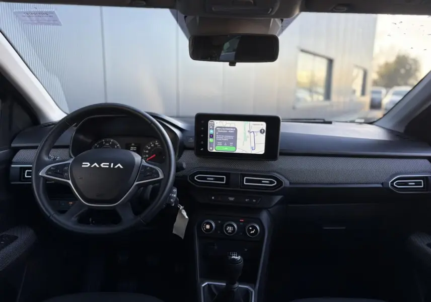 Vue intérieure avant du tableau de bord du Dacia Jogger 2025 avec écran tactile GPS et volant noir multifonction.