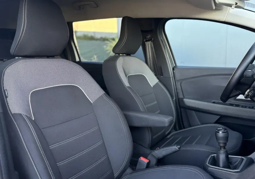 Vue intérieure côté droit du Dacia Jogger 2025, montrant les sièges avant noirs avec surpiqûres blanches et levier de vitesse manuel.