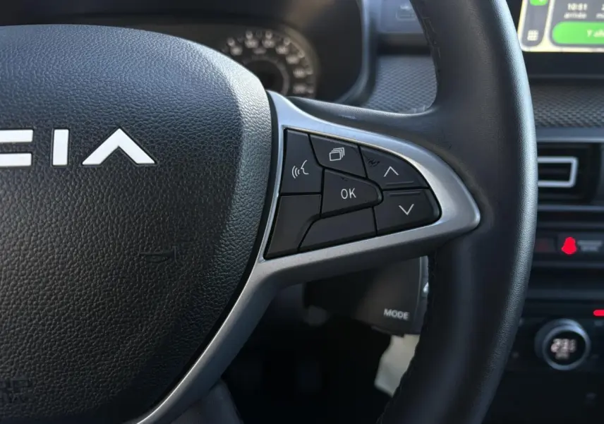 Gros plan sur le volant noir de la Dacia Jogger 2025 avec commandes multifonctions et partie centrale texturée.