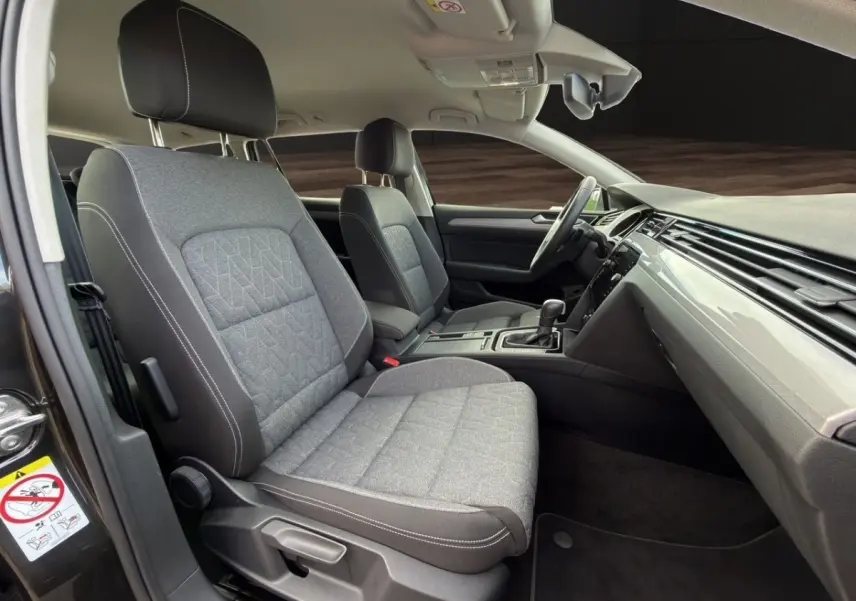 Intérieur avant de la Volkswagen Passat 2.0 TDI 2022, vue côté conducteur avec sièges gris et tableau de bord noir.