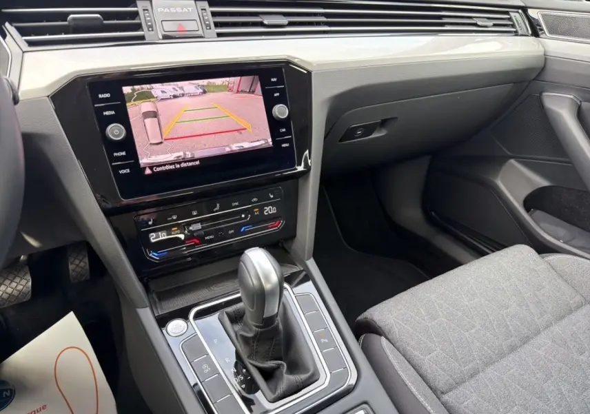 Vue intérieure côté passager de la Volkswagen Passat gris foncé, avec écran tactile affichant la caméra de recul.