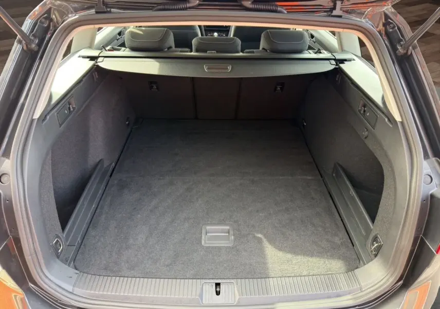 Vue arrière du coffre spacieux et propre d’une Volkswagen Passat gris foncé avec banquette arrière visible.