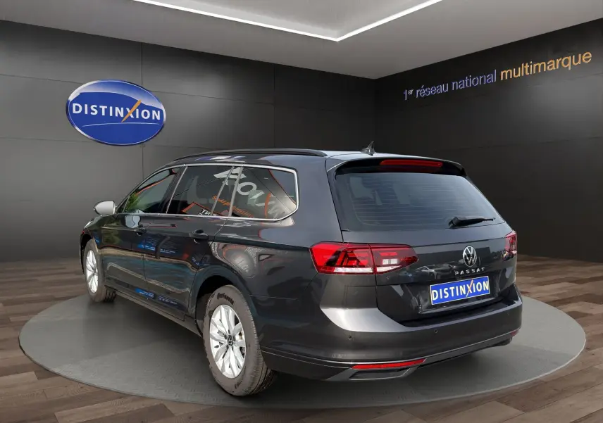 Volkswagen Passat break gris foncé vue 3/4 arrière droit, feux arrière LED et jantes alliage visibles.