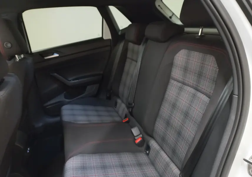 Vue intérieure côté arrière droit de la Volkswagen Polo 2024, sièges arrière à motif écossais avec surpiqûres rouges.