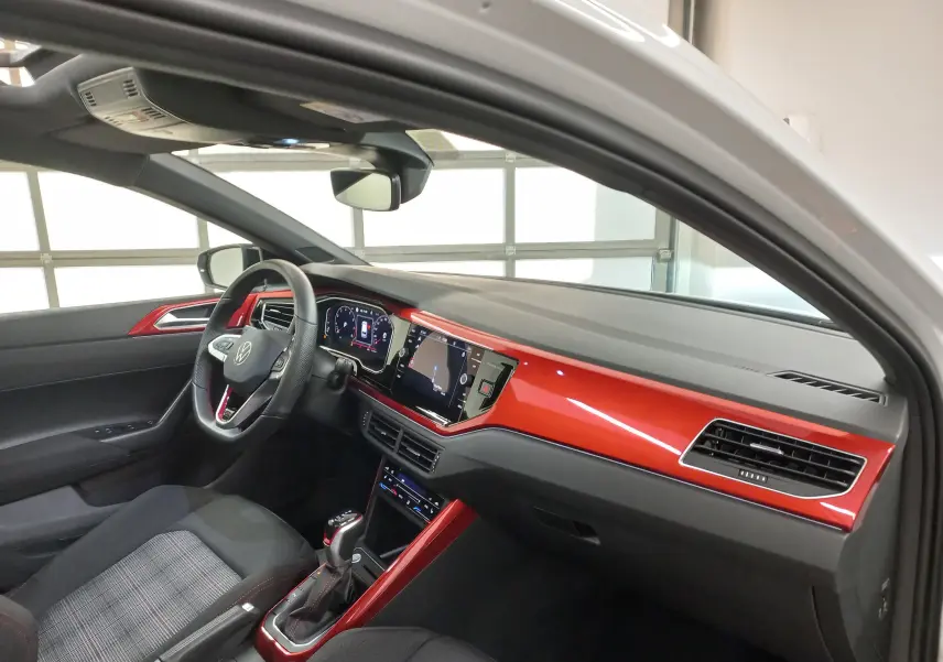 Vue intérieure côté conducteur de la Volkswagen Polo GTI 2024 avec tableau de bord et inserts rouges brillants.