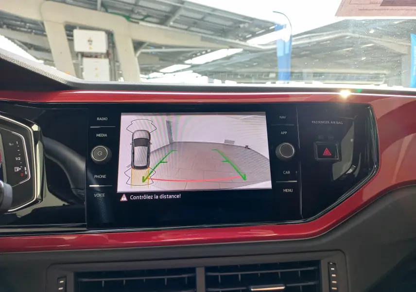 Vue rapprochée de l'écran central rouge de la Volkswagen Polo 2024 affichant la caméra de recul avec guidage vert et rouge.