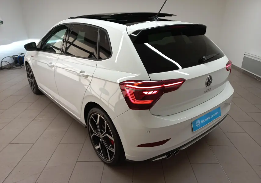 Vue 3/4 arrière droite d'une Volkswagen Polo GTI blanche avec toit noir ouvrant et jantes alliage 18 pouces.