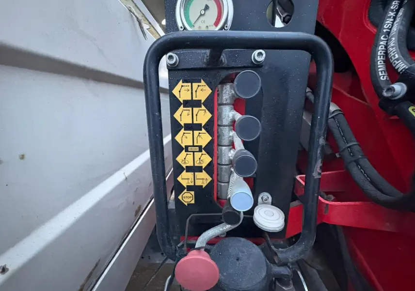Gros plan sur les commandes de la grue rouge Palfinger du côté gauche de la benne blanche du camion Iveco Daily Chassis Cabine.