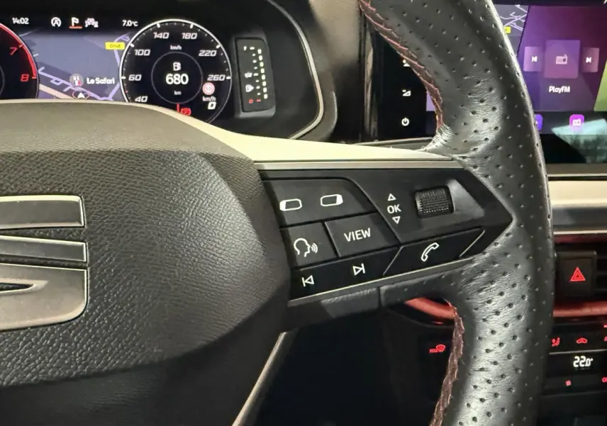 Gros plan sur le volant cuir et alu de la SEAT Ibiza 2024, avec commandes multifonctions et tableau de bord numérique.