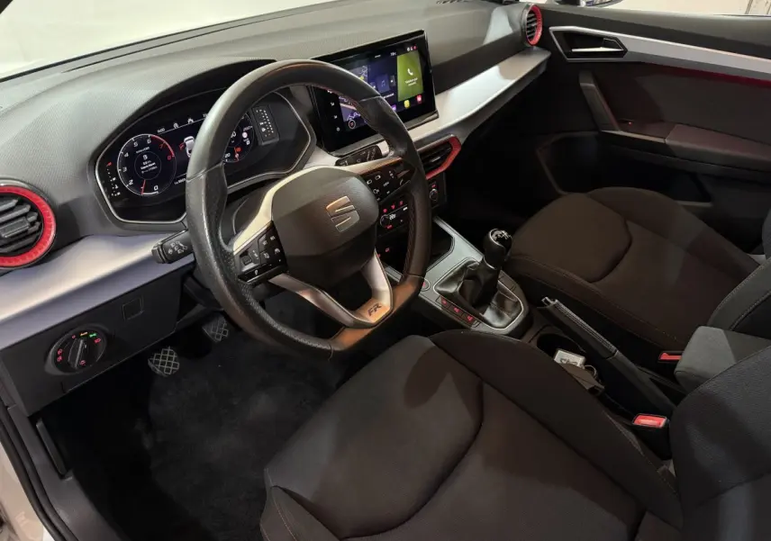 Vue intérieure côté conducteur de la SEAT Ibiza 1.0 TSI 110 FR 2024 avec volant cuir alu et écran tactile central.