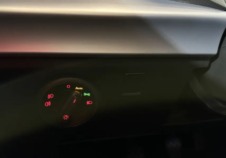 Gros plan sur le bouton de commande des phares dans l'habitacle sombre d'une SEAT Ibiza blanche 2024.
