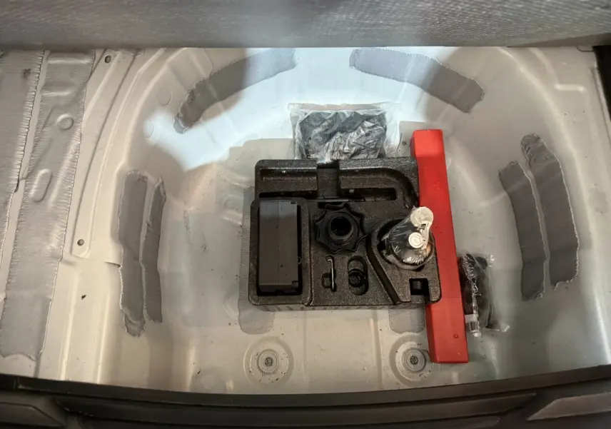 Vue plongeante sur le compartiment de rangement sous le coffre d'une SEAT Ibiza blanc, avec kit de réparation pneus.