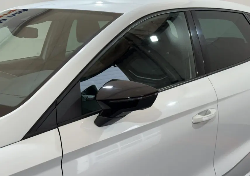 Vue côté gauche rapprochée d’une SEAT Ibiza blanche 2024, mettant en valeur la portière et le rétroviseur noir brillant.