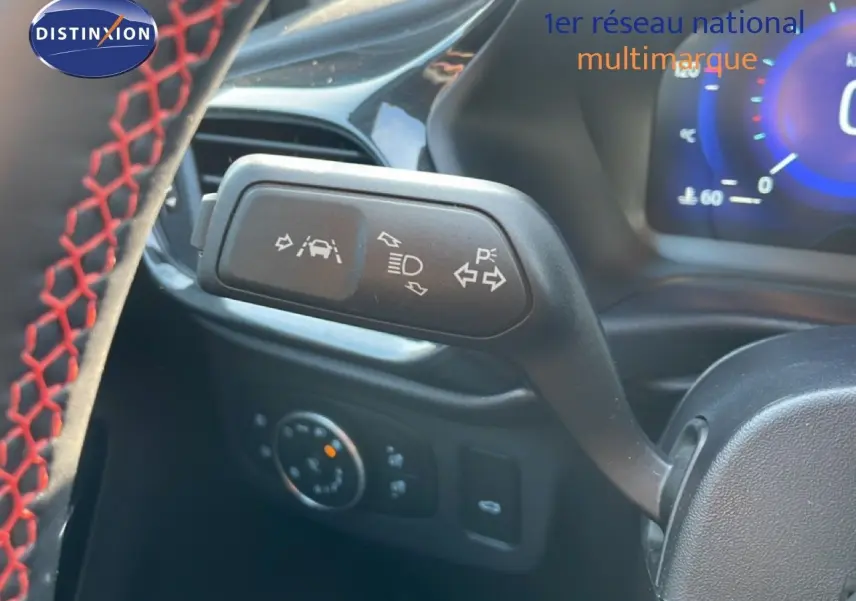 Gros plan sur la commande de clignotant et aides à la conduite du Ford Puma noir Agate Métal, intérieur avec volant cuir noir à surpiqûres rouges.