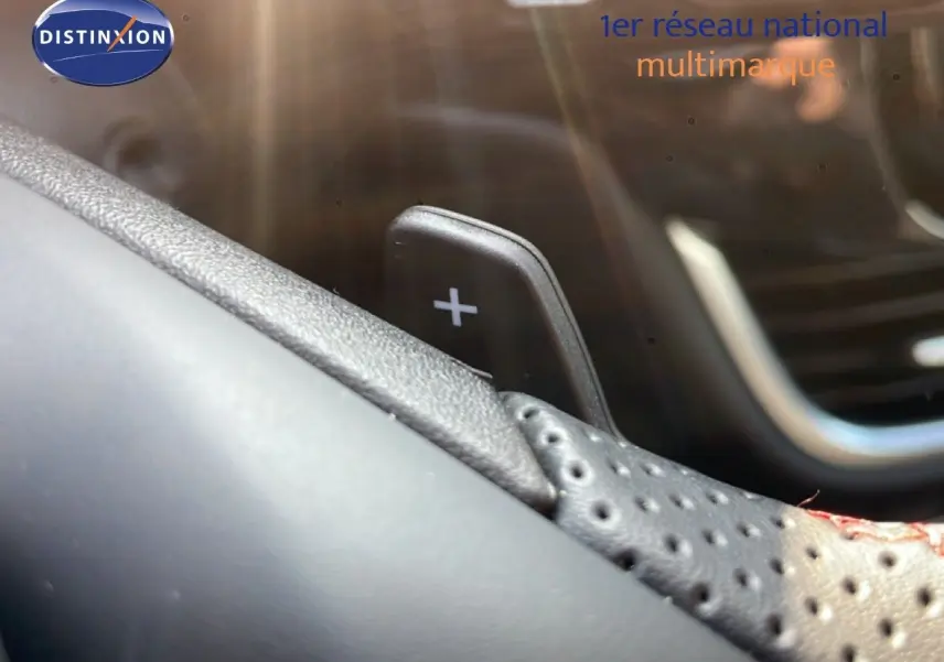 Gros plan sur la palette de changement de vitesse "+" en cuir perforé noir à surpiqûres rouges dans un Ford Puma 2023.