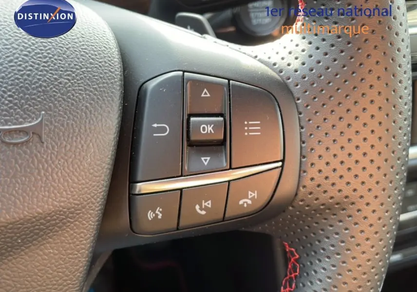 Gros plan sur les commandes multifonctions à gauche du volant perforé noir du Ford Puma 2023 finition ST-LINE.