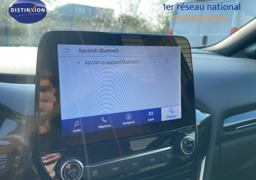Vue intérieure du tableau de bord du Ford Puma 2023, écran tactile affichant les réglages Bluetooth, ambiance moderne noire.
