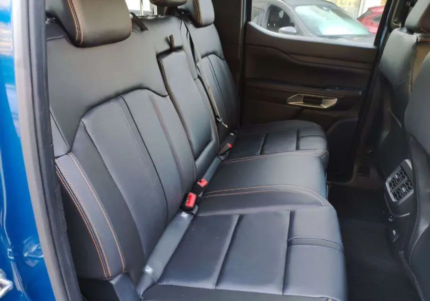 Vue intérieure côté droit des sièges arrière en cuir noir avec surpiqûres orange du Ford Ranger 2026 Bleu Lightning.