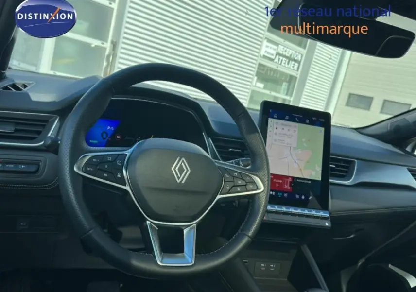 Vue intérieure centrée sur le volant noir de la Renault SYMBIOZ blanc, avec écran tactile vertical et tableau de bord numérique.