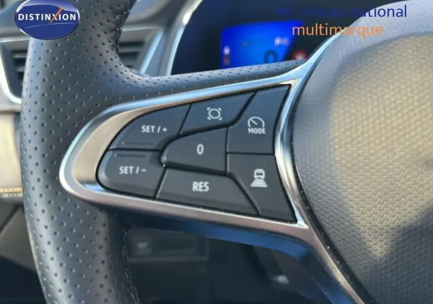 Gros plan sur le côté gauche du volant perforé du Renault Symbioz blanc, avec commandes de régulateur de vitesse.